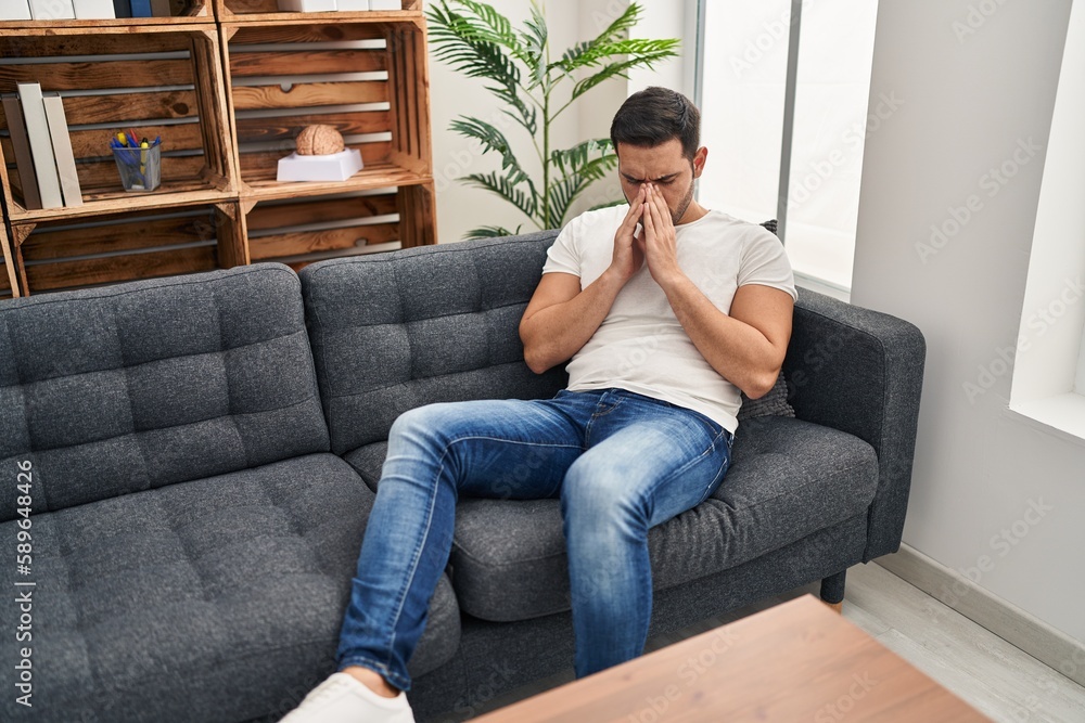Young hispanic man stressed having mental therapy sitting on sofa at psychology center Young hispanic man stressed having mental therapy sitting on sofa at psychology center