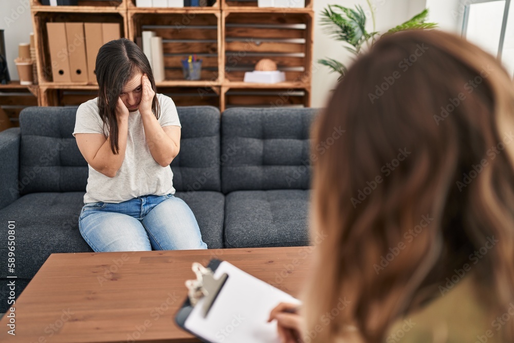 Hispanic girl with down syndrome doing therapy with hand on head for pain in head because stress. suffering migraine. Hispanic girl with down syndrome doing therapy with hand on head for pain in head because stress. suffering migraine.
