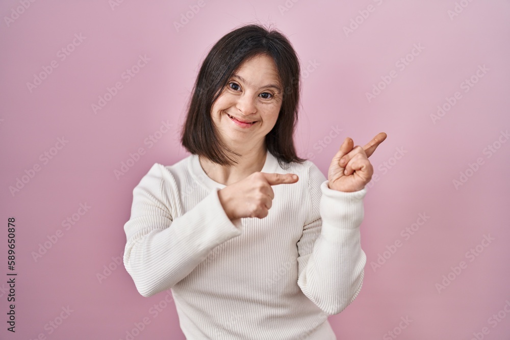 Woman with down syndrome standing over pink background smiling and looking at the camera pointing with two hands and fingers to the side. Woman with down syndrome standing over pink background smiling and looking at the camera pointing with two hands and fingers to the side.