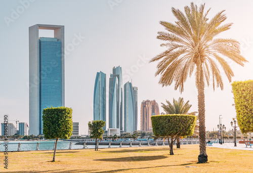 picturesque park in Abu Dhabi offers stunning views of the city's sleek and modern skyline, with towering skyscrapers rising up against the blue waters of the Persian Gulf. © EdNurg