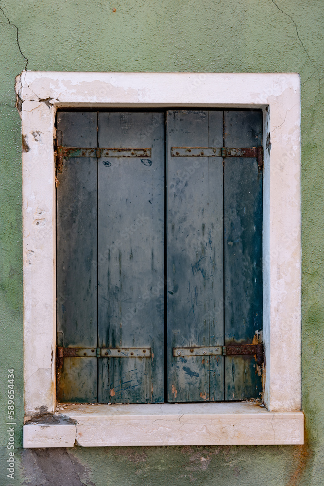 Faded old rustic green wooden door from Venice Italy. The island of Burano tourist destination fishing island famous for it's coloured houses