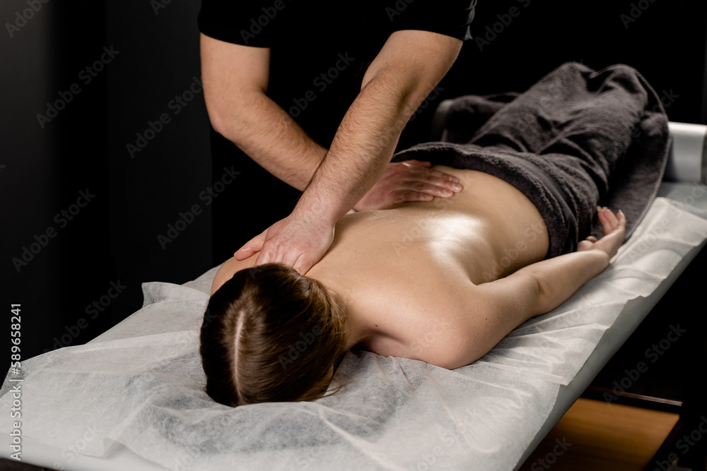Attractive girl is relaxing on classic massage procedure in spa. Manual therapy. Masseur is doing back massage. Attractive girl is relaxing on classic massage procedure in spa. Manual therapy. Masseur is doing back massage.
