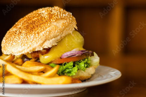 Image of close-up details of a large hamburger with french fries, loaded with bacon and cheese