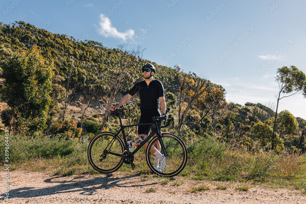 Young male with bicycle relaxing during training enjoying the view