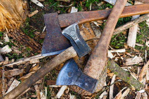 Woodcutter's axes with wooden handles. The hatchet .Harvesting firewood in the village. Logs and timber on the ground in the countryside.