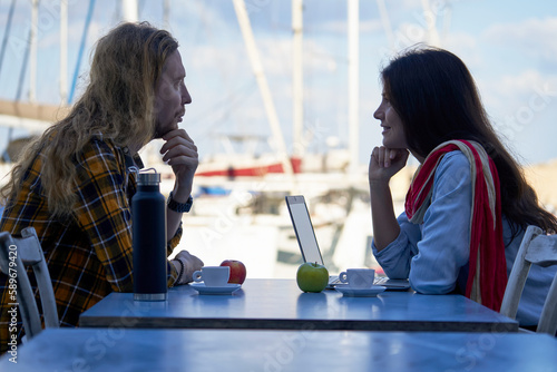 Young couple communicating at the table in the open cafe photo