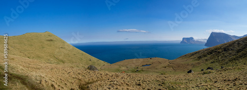 Kallur lighthouse hiking path between the yellow grass landscape of Kalsoy with Kunoy and Vidoy islands at sight