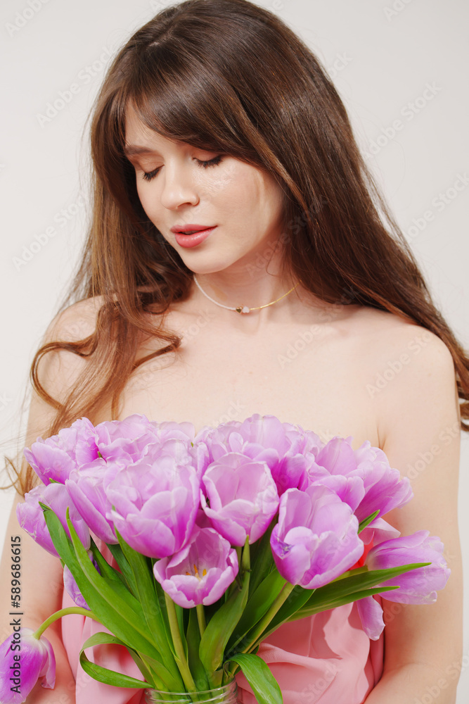 portrait of a woman topless with a bouquet of tulips on a white background.