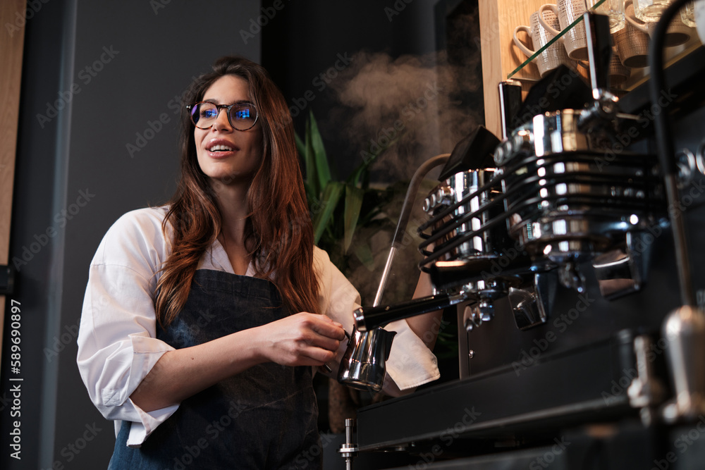 Barista standing next to a coffee machine in a coffee shop and heating