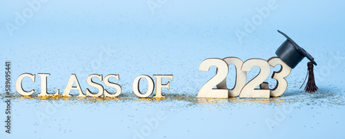 Class of 2023 concept. Wooden number 2023 with graduated cap on blue background. Banner format photo