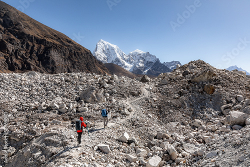 Hikers crossing Ngozumpa glacier between Gokyo and Dragnag with Cholatse in the background photo
