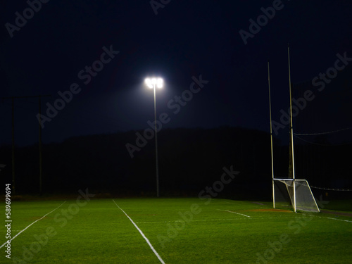 Training ground with grass illuminated by modern powerful LED lights. Efficient modern technology. Nobody. Sport field with tall goal posts for rugby, camogie, hurling and Gaelic football. Irish sport photo