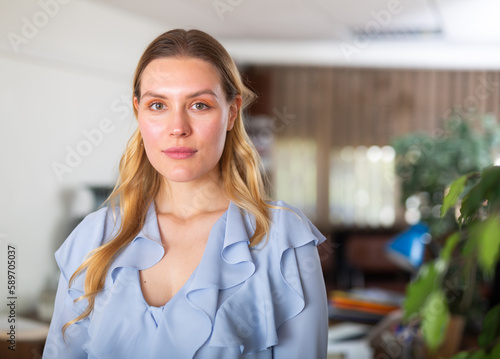 Portrait of elegant confident female employee posing in modern office interior