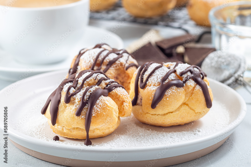 Profiteroles with whipped cream and chocolate filling, covered with melted chocolate, horizontal Profiteroles with whipped cream and chocolate filling, covered with melted chocolate, horizontal