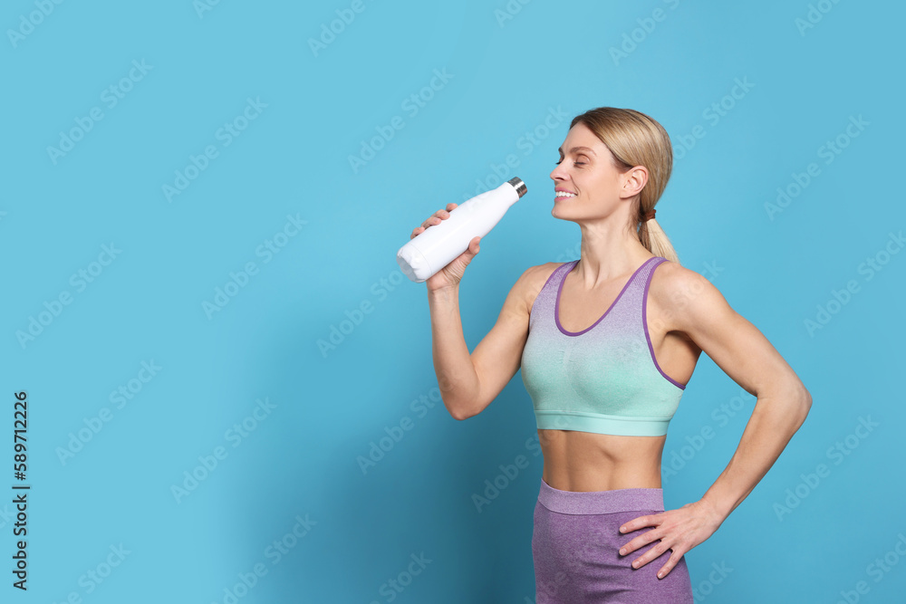 Sportswoman with thermo bottle on light blue background, space for text Sportswoman with thermo bottle on light blue background, space for text