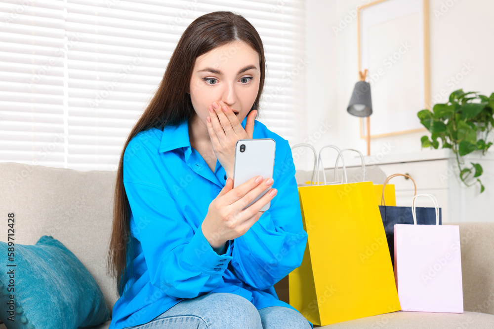 Special Promotion. Emotional young woman looking at smartphone on sofa indoors Special Promotion. Emotional young woman looking at smartphone on sofa indoors