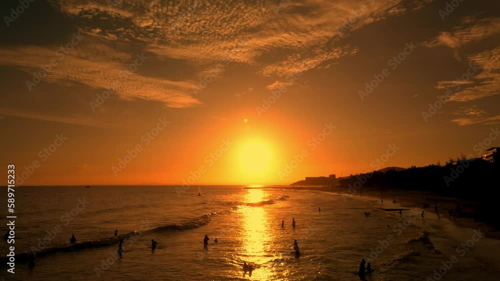 Surfers rides big wave against backdrop beautiful sunset on the sea Vietnam. People on vacation swimming in the sea, happy with riding on sea wave on surfboard. Surf sea background at sunset. 4K Surfers rides big wave against backdrop beautiful sunset on the sea Vietnam. People on vacation swimming in the sea, happy with riding on sea wave on surfboard. Surf sea background at sunset. 4K