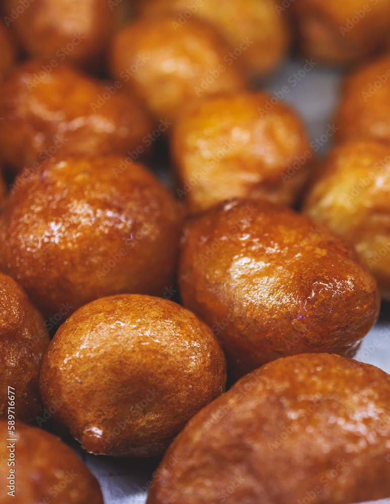 Close-up view of Loukoumades dessert, greek donuts with honey and walnut, traditional greek lokma sweets and delights served in bakery cafe in Athens, Attica, Greece Close-up view of Loukoumades dessert, greek donuts with honey and walnut, traditional greek lokma sweets and delights served in bakery cafe in Athens, Attica, Greece
