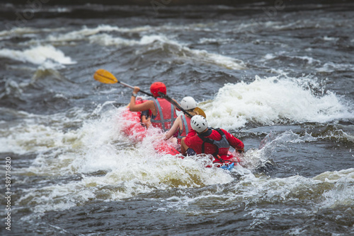 Raft boat during whitewater rafting extreme water sports on water rapids, kayaking and canoeing on the river, water sports team with a big splash of water, 3 persons in a raft boat