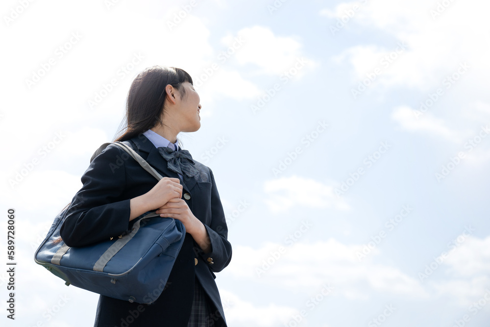 屋上の青空背景で塾や予備校、受験などに顔無しで使いやすい振り返るブレザーの学生さん  目標や合格のイメージに　