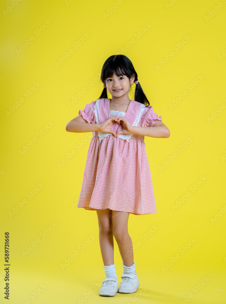 image full body of asian little girl posing on a yellow background image full body of asian little girl posing on a yellow background