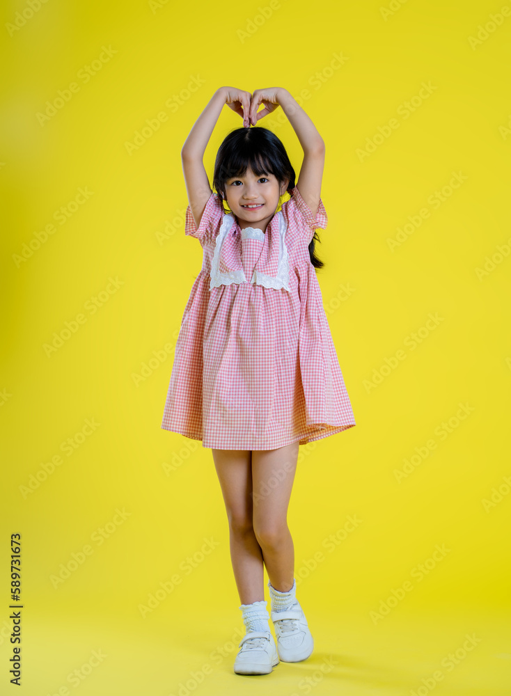 image full body of  asian little girl posing on a yellow background