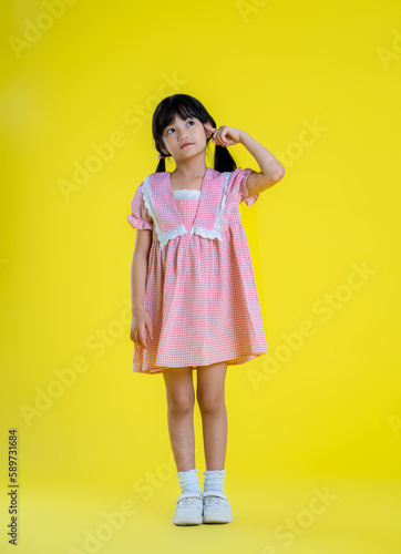 image full body of asian little girl posing on a yellow background