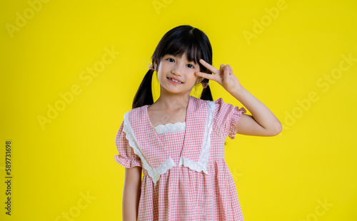 image of asian little girl posing on a yellow background