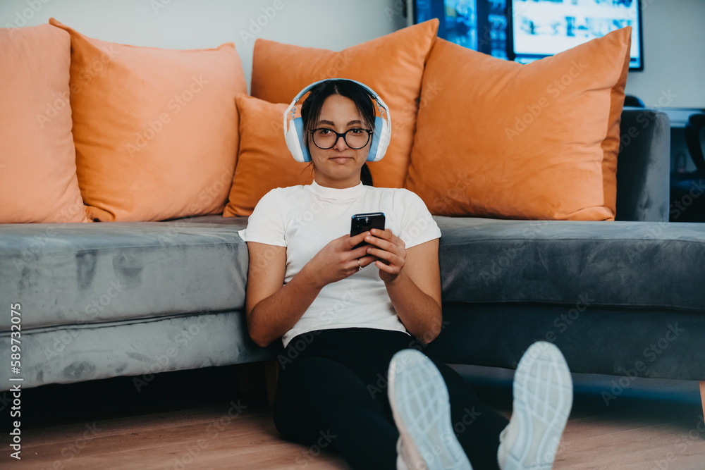 A woman doing home workout with headphones and smartphone for a video call. Reflects modern lifestyle, blending technology, health, and connectivity for holistic well-being. A woman doing home workout with headphones and smartphone for a video call. Reflects modern lifestyle, blending technology, health, and connectivity for holistic well-being.