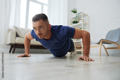 Man sportsman training at home, push-up exercises for arm, leg and back muscles, strong body and correct posture, the concept of health and beauty