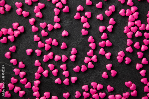 Pink heart sugar sprinkles scattered on dark