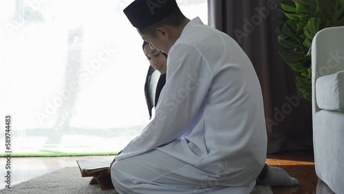 Asian Muslim family reciting surah al-Fatiha passage of the Qur'an, daily prayer at home, a single act of sujud called a sajdah or prostration . Quran holy book is a public item of all photo