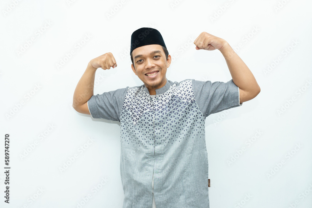 Naklejka premium Asian Indonesian Muslim man raises his hands and show muscles as strong gesturing