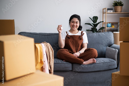 Satisfied homeowner. portrait of happy young asian woman buyer renter of new modern home apartment holding key demonstrating wellbeing wealth celebrate achievement