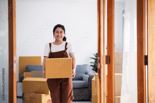 New house, moving and asian woman carrying boxes while feeling proud and excited about buying a house with a mortgage loan. Young asian woman first time buyers unpacking in dream home, apartment