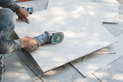 worker cutting a tile using an angle grinder at construction site