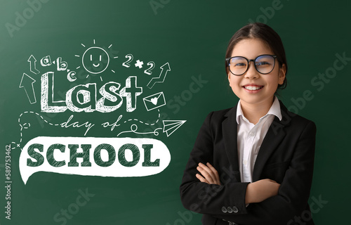 Cute Asian girl near blackboard with text LAST DAY OF SCHOOL photo