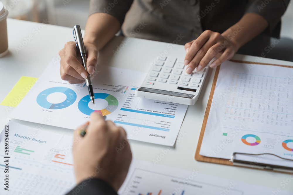 Team of business people is calculating with a calculator and discussing to record company financial growth statistics using graphs. The chart is a reference for auditing and analyzing the summary. Team of business people is calculating with a calculator and discussing to record company financial growth statistics using graphs. The chart is a reference for auditing and analyzing the summary.