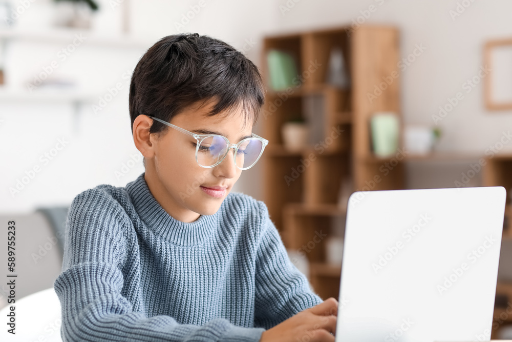 Little boy in eyeglasses using laptop at home Little boy in eyeglasses using laptop at home