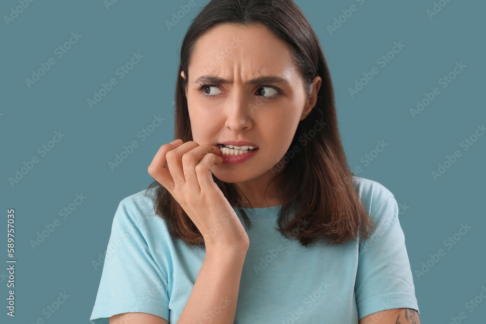 Young woman biting nails on blue background, closeup Young woman biting nails on blue background, closeup