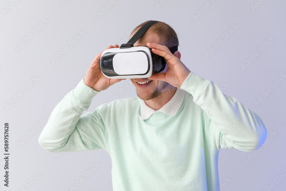 Young man using VR glasses on light background Young man using VR glasses on light background