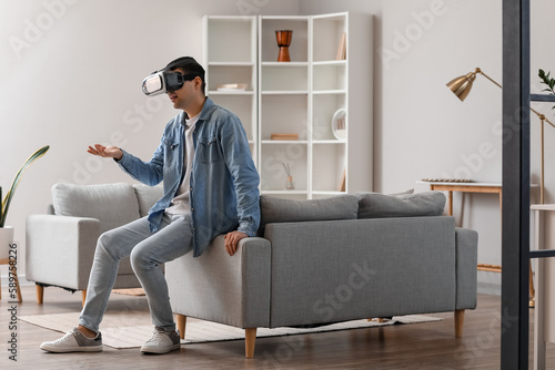 Young man using VR glasses at home © Pixel-Shot