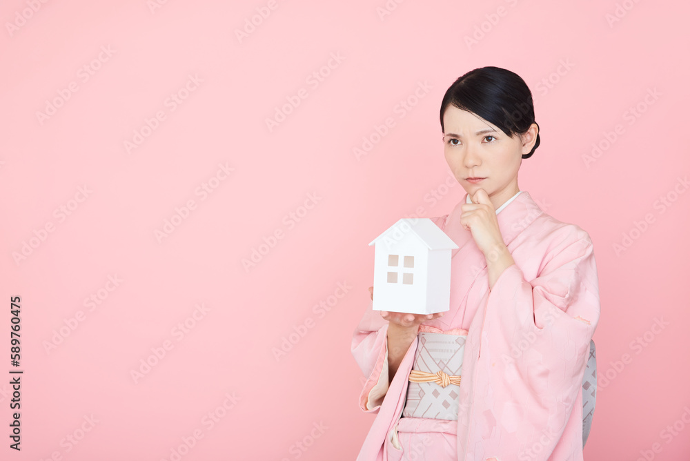 家の模型をもつ着物を着た女性