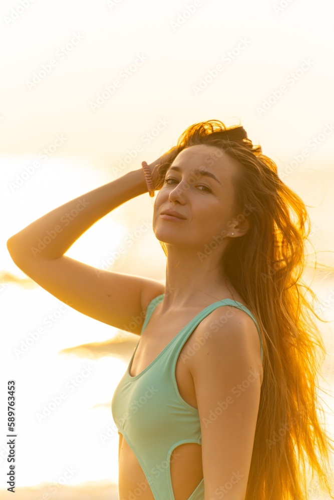Beautiful caucasian sexy woman in bikini swimsuit by the beach with superb sunset and sun rays shinning across the sea Beautiful caucasian sexy woman in bikini swimsuit by the beach with superb sunset and sun rays shinning across the sea
