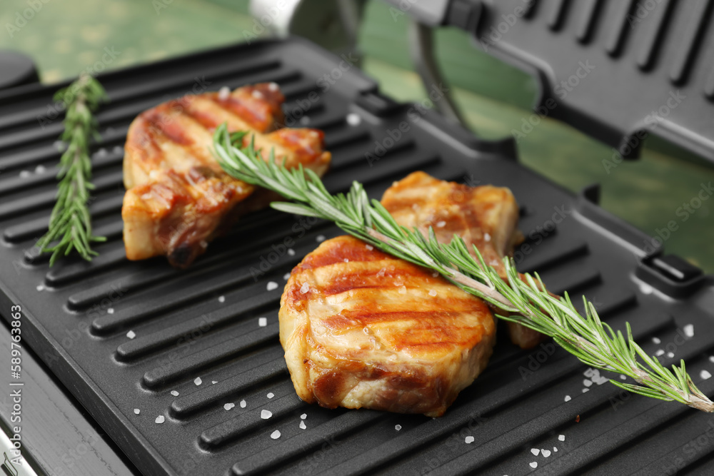 Delicious steaks and rosemary on modern electric grill, closeup Delicious steaks and rosemary on modern electric grill, closeup