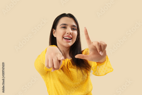 Foto Young woman showing loser gesture on beige background