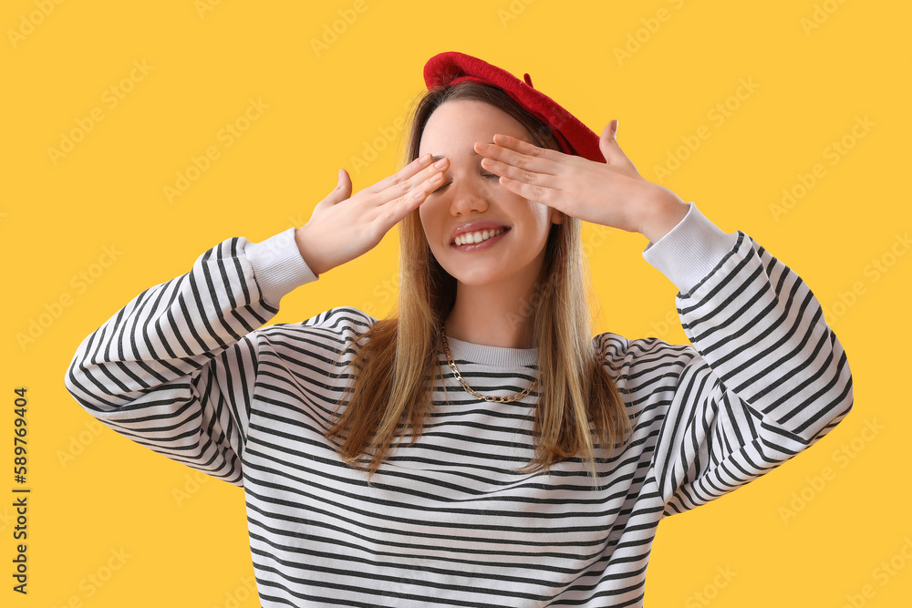 Young woman closing her eyes with hands on yellow background Young woman closing her eyes with hands on yellow background