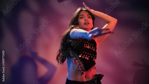Fashion mixed race woman belly dancer seductive movement flexible body posing neon studio slowmo