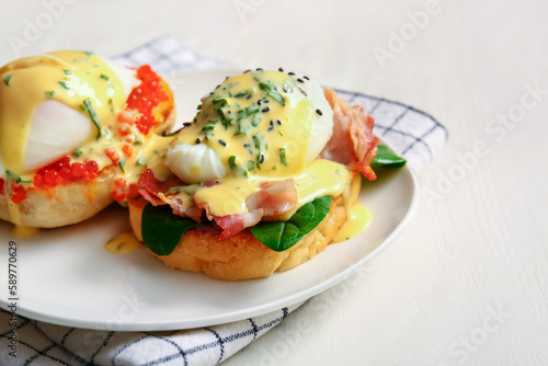 Plate with tasty eggs Benedict on white wooden table, closeup