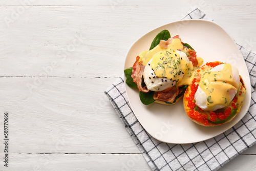 Plate with tasty eggs Benedict on white wooden table